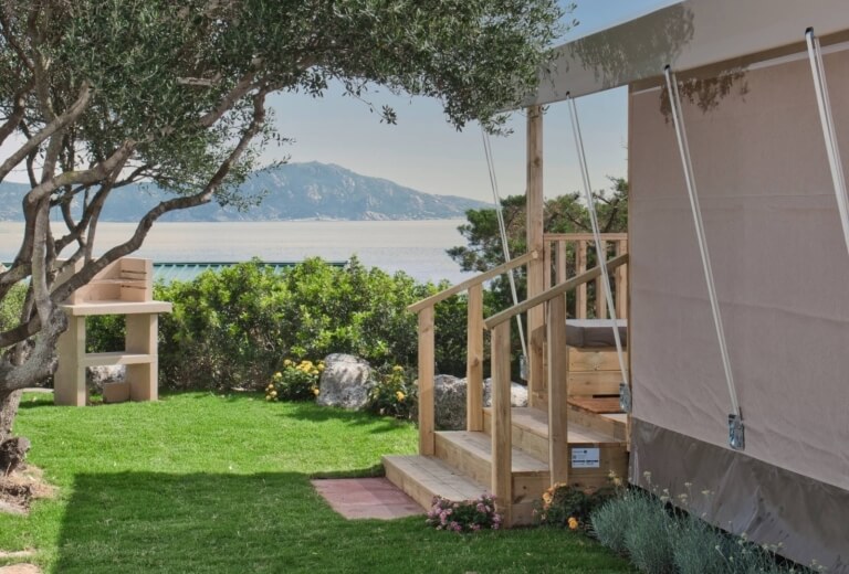 Tenda canvas, barbecue, altana con altalena, acqua calma e montagna.