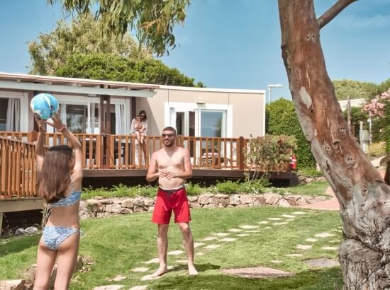 Drei Personen spielen mit einem Ball in einem malerischen Garten an einem sonnigen Tag.