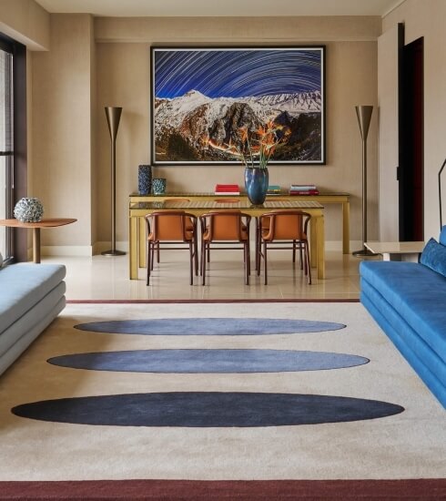 Elegant room with snow-capped mountain view, modern furniture, blue and grey sofas, and decorative accents.