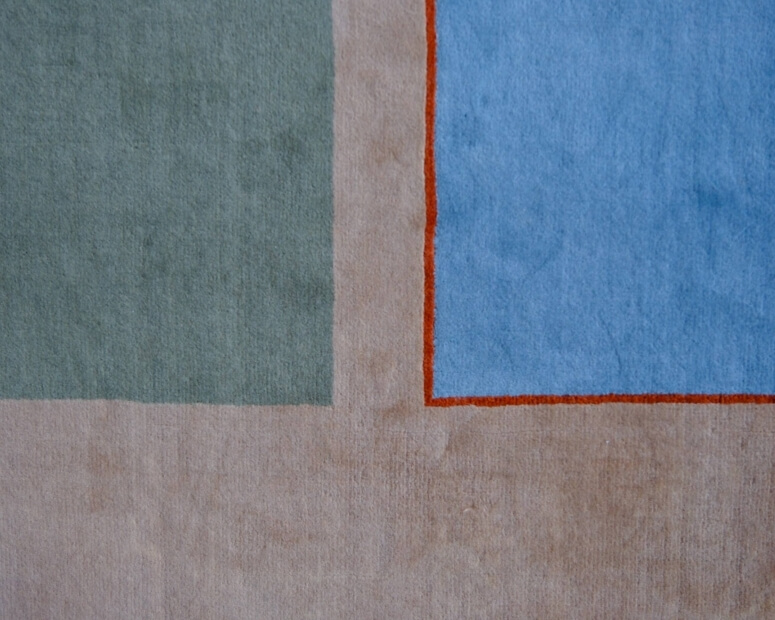 Abstract composition of colored squares in beige, green, and blue, with texture variations and an orange border.