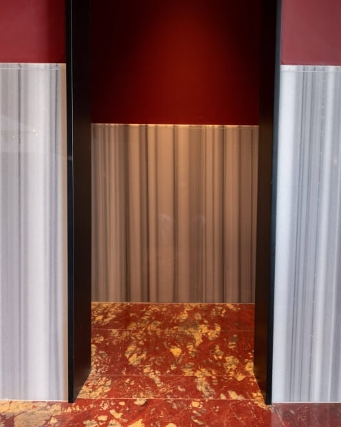 A striking composition of red and black marble with gold and white accents, featuring distinct textured sections and a black door.