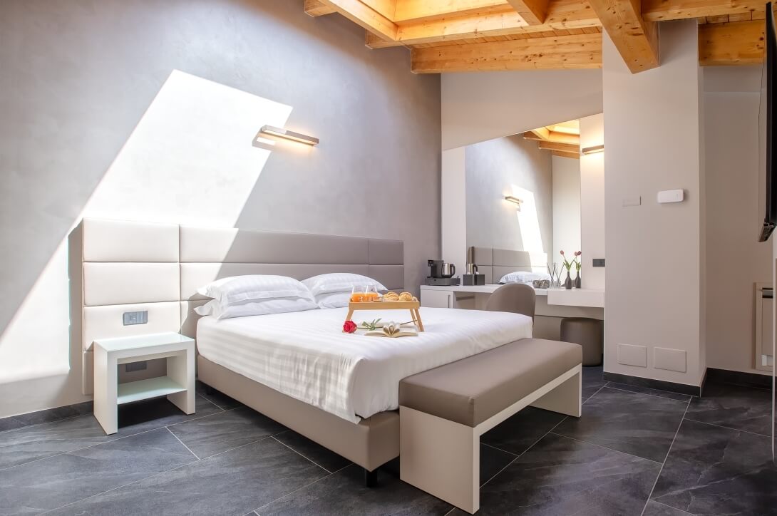 Camera d'hotel serena con letto grande, biancheria bianca, vassoio con succo d'arancia e dolci, e decorazioni rustiche.