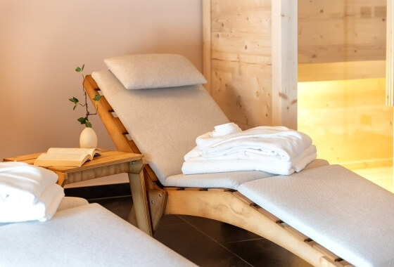 Impostazione di spa con tre sedie a sdraio in legno, asciugamani bianchi e illuminazione calda.