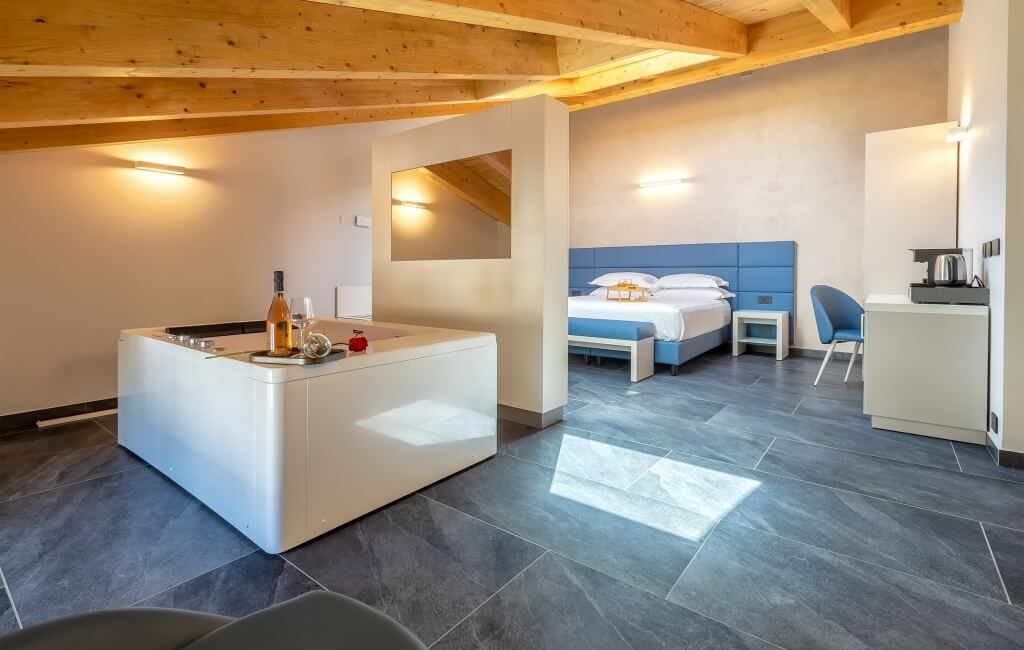 Camera d'hotel moderna con letto, angolo cottura e area salotto, illuminata da luce naturale e decorata con eleganza.