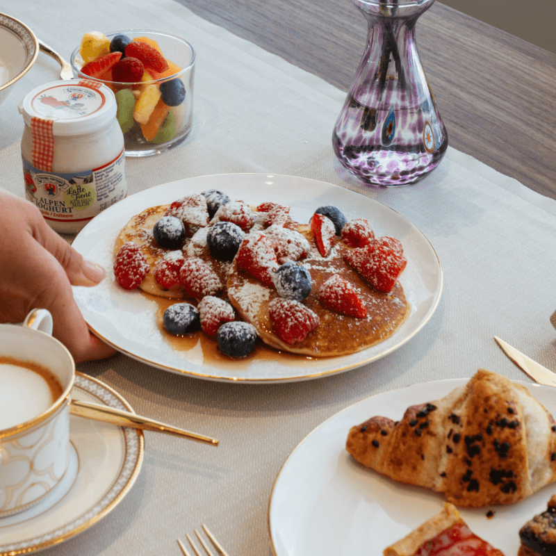 Pancakes con frutti di bosco, yogurt, insalata di frutta e caffè.