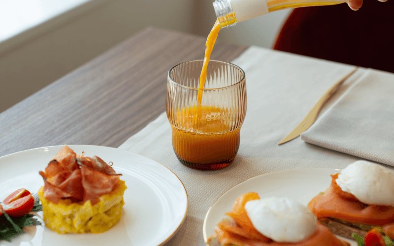 Succo d'arancia versato in un bicchiere con piatti di cibo.