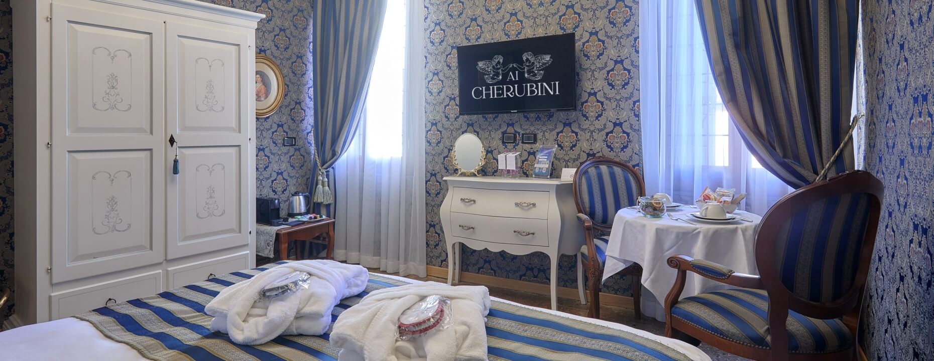 Camera d'hotel elegante con armadio, letto a righe e tavolo da caffè.