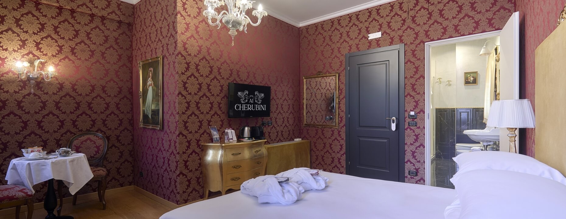 Camera d'hotel elegante con letto, tavolo, TV e bagno.