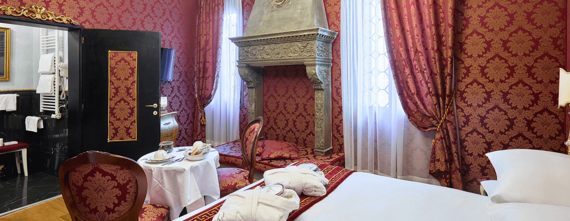 Camera d'hotel con letto, accappatoi, colazione e camino.