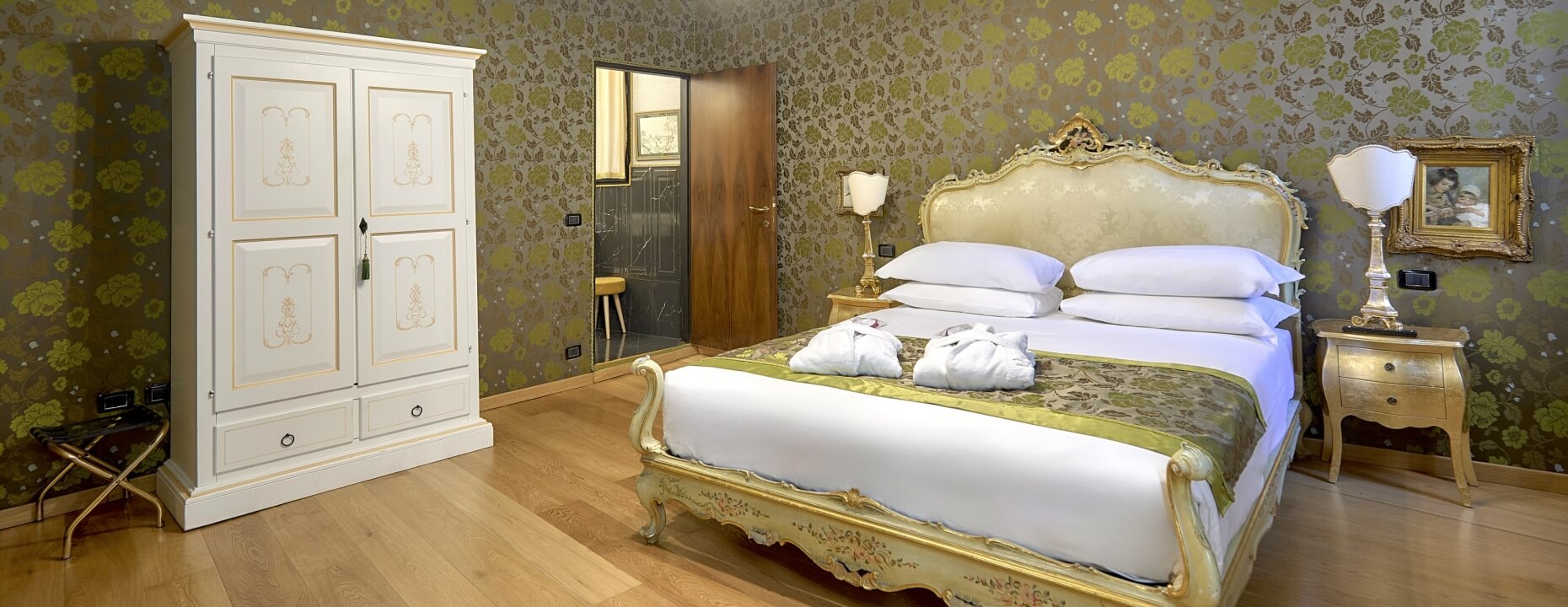 Camera d'hotel con letto grande, armadio bianco e decorazioni eleganti.