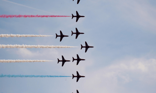 Formazione di aerei scuri che volano con scie tricolori.