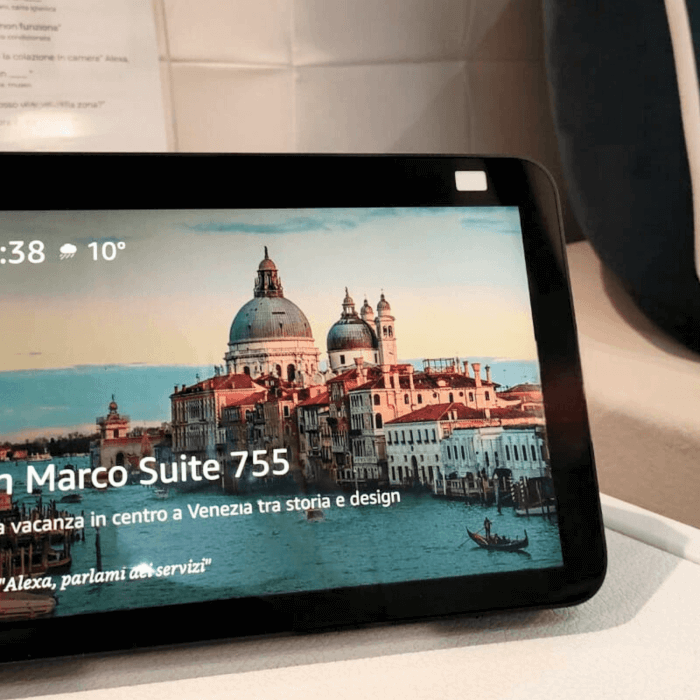 Tablet displaying a photo of Venice with time and temperature, text about a vacation rental in a hotel room setting.