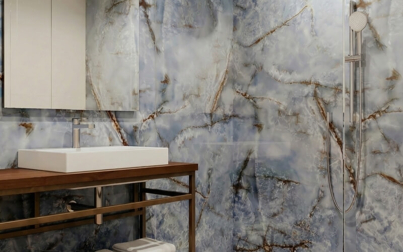 Bagno con lavabo bianco, mobile in legno e piastrelle marmorizzate.