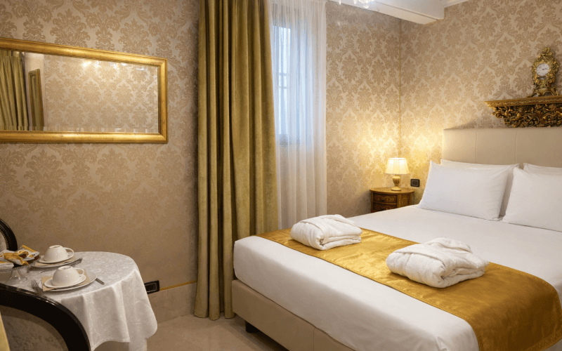 Camera d'hotel elegante con letto, tavolo e decorazioni dorate.