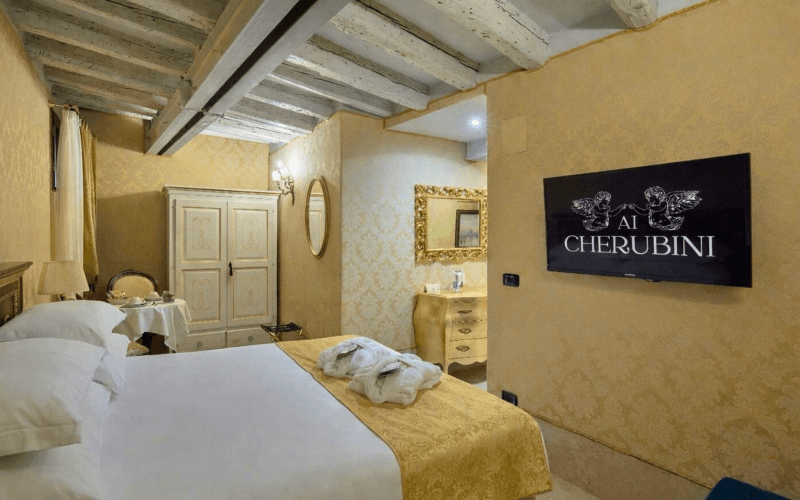 Camera d'hotel con letto, armadio, tavolo e TV a schermo piatto.