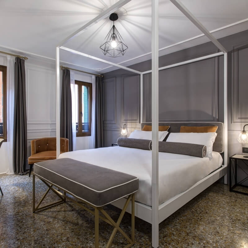 Camera d'hotel con letto a baldacchino e arredi eleganti.