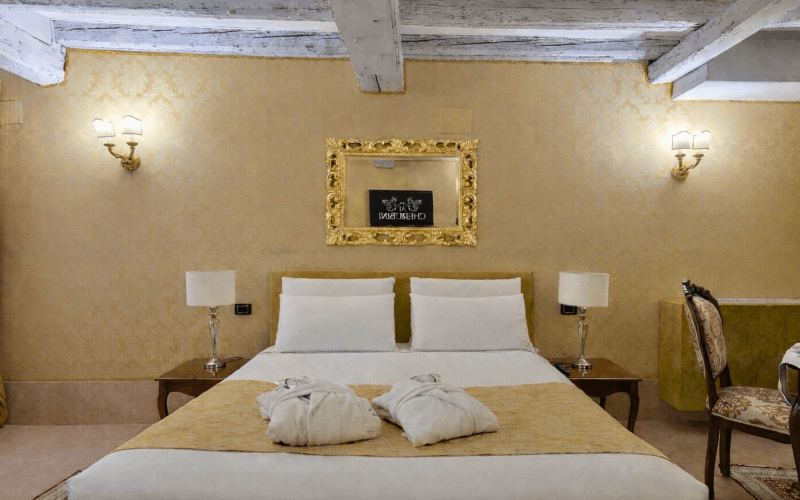 Camera d'hotel elegante con letto, specchio dorato e mobili in legno.