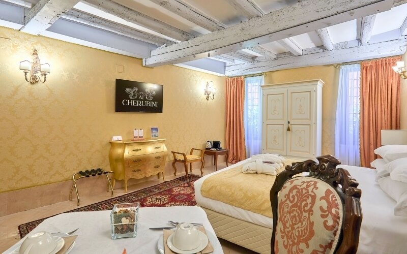 Camera d'hotel con letto, armadio, televisore e tavolino con set da tè.