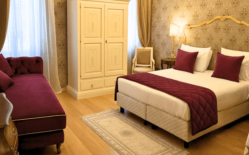 Camera d'hotel con letto, chaise longue, armadio e tappeto.