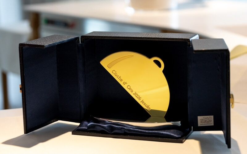 Premio d'oro a forma di cloche in una custodia blu.
