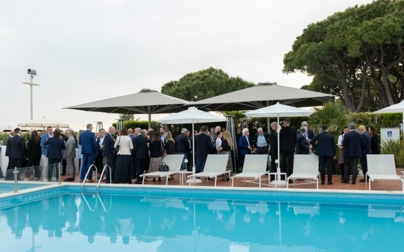 Gruppo di persone in abiti formali attorno a una piscina blu.