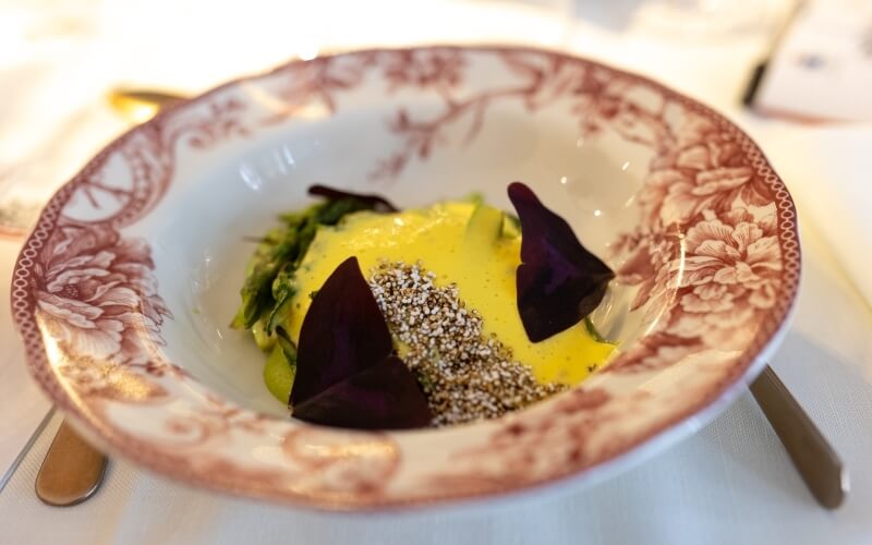 Ciotola bianca con piatto verde, salsa gialla e guarnizione viola.