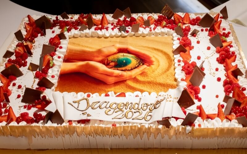 Torta decorata con frutta, cioccolato e immagine "Dragondoro 2026".