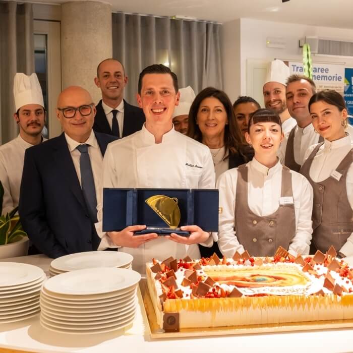 Gruppo di persone con torta decorata e premio dorato.