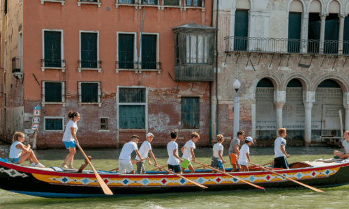 Gondola with children holding oars on a canal. Gondola con bambini che tengono remi su un canale.