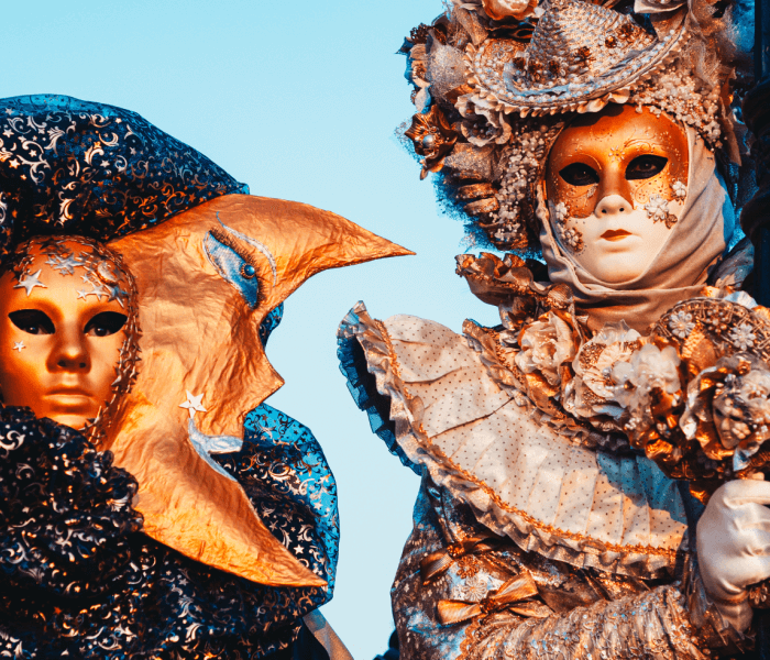 Due figure in costumi elaborati e maschere su sfondo blu.