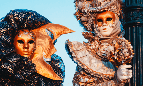 Due persone in maschere elaborate da carnevale, una dorata e l'altra veneziana.