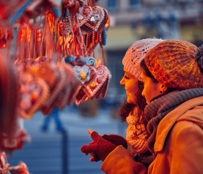 Due donne ammirano ornamenti a forma di cuore in un ambiente invernale.