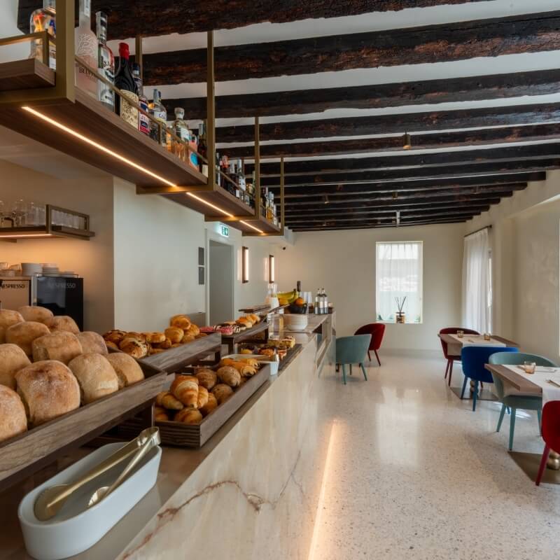 Buffet con pane, dolci, macchina da caffè e tavoli.