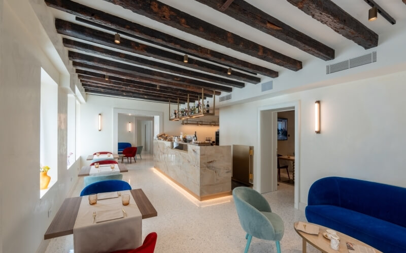 Interno ristorante con bar in marmo e travi in legno.