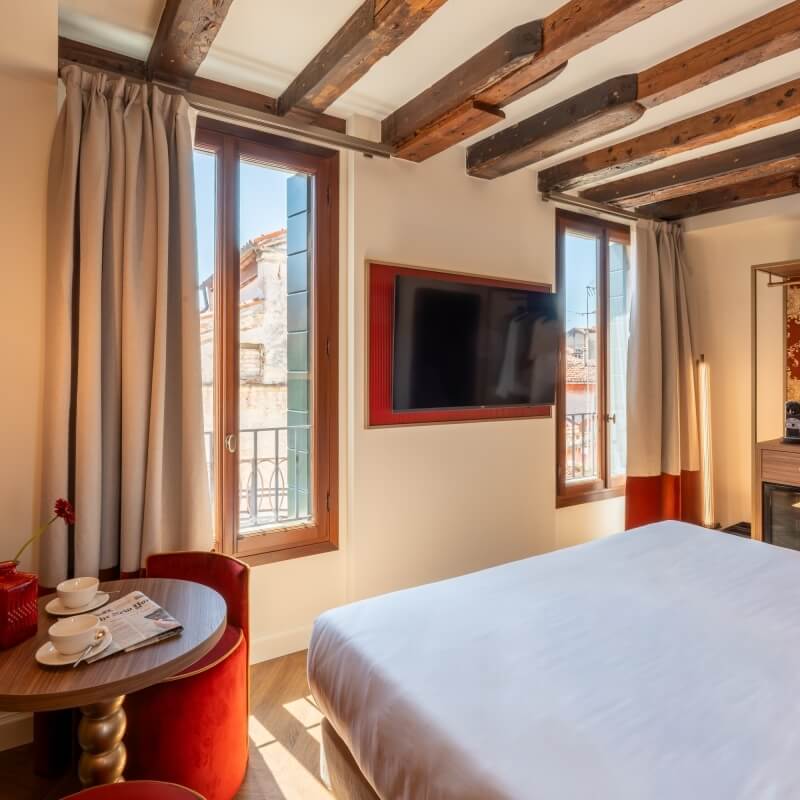 Camera d'hotel con letto, TV rossa, tavolo e finestre.