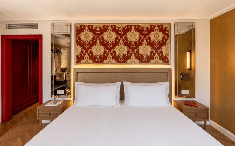 Camera d'hotel con letto grande, testata decorativa e tavolino.