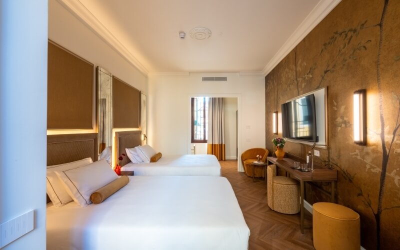 Hotelzimmer mit zwei Betten, Spiegelwänden und einem Schreibtisch.