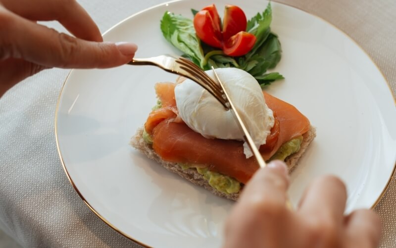 Toast con avocado, salmone affumicato, uovo in camicia e pomodorini.