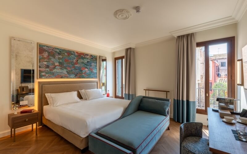 Helles Hotelzimmer mit großem Bett, Chaise Lounge und Schreibtisch.