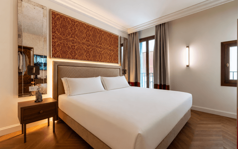 Camera d'hotel con letto grande, specchio e pannello decorativo.