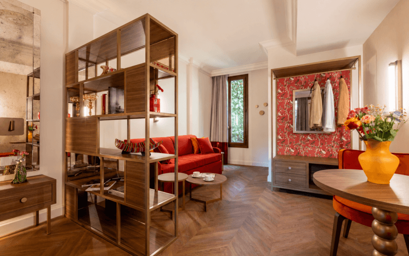 Camera d'hotel con divano rosso, tavoli e armadio.