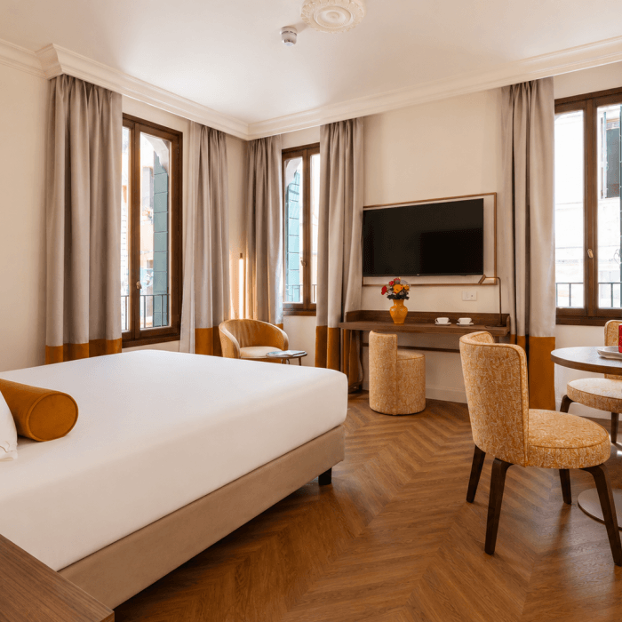 Camera d'hotel con letto, scrivania, tavolo rotondo e finestre.