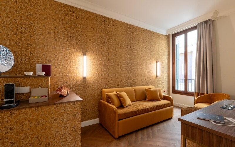 Camera d'hotel con divano, scrivania e macchina da caffè.