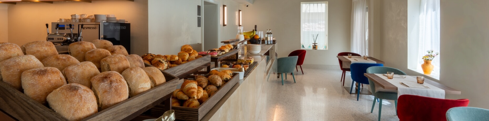 Buffet con dolci, macchina da caffè Nespresso e tavoli decorati.