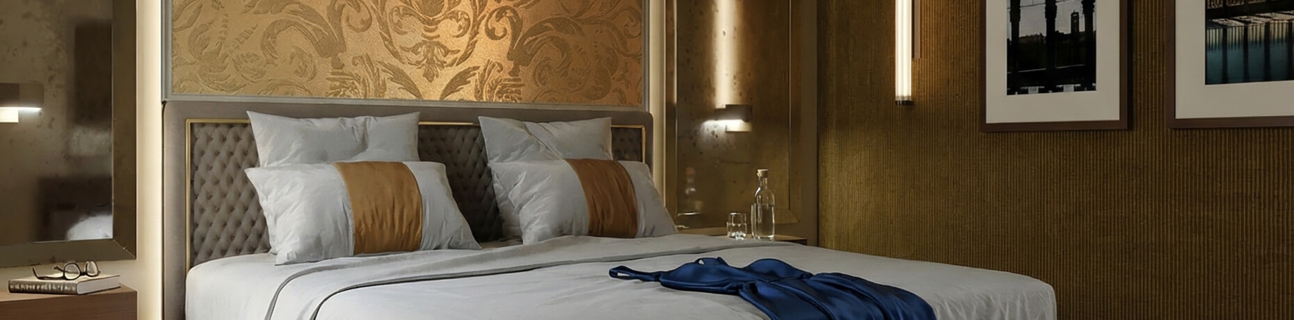 Camera d'hotel con letto bianco, decorazioni dorate e tavolino.