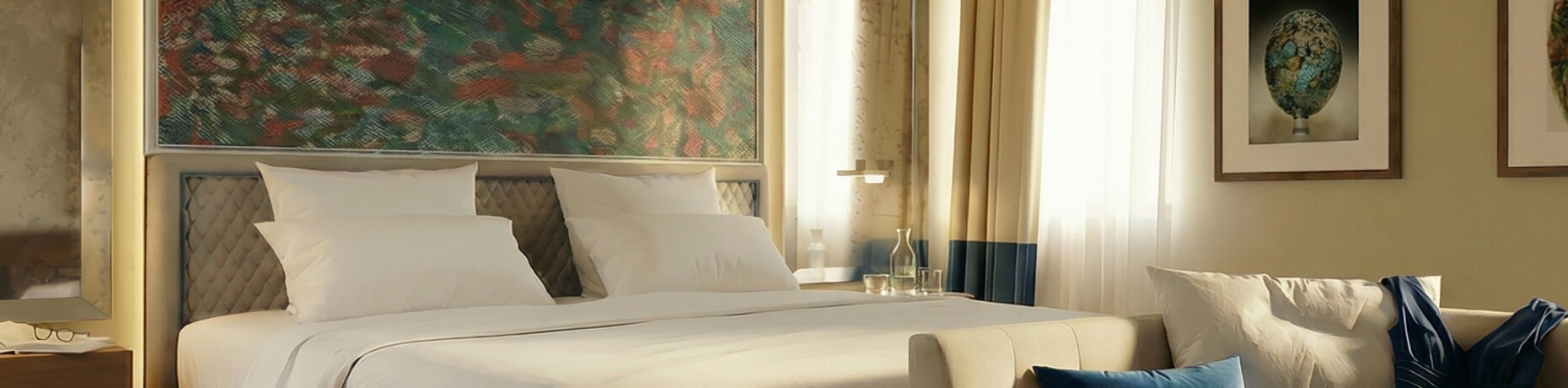 Helle Hotelzimmer mit Bett, Sofa, Kunstwerk und Fensterdekoration.