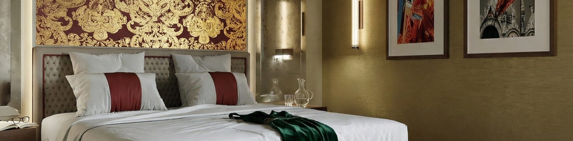 Camera d'hotel con letto, decorazioni rosse e dorate, e tavolo con caraffa.