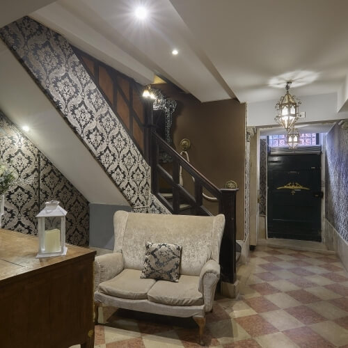 Stanza con scala, divano, scrivania e pavimento a scacchi.