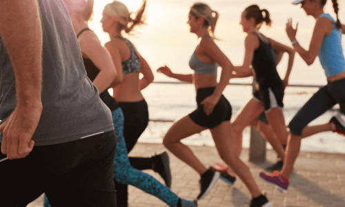 Gruppo di persone che corrono all'aperto vicino a un corpo d'acqua.
