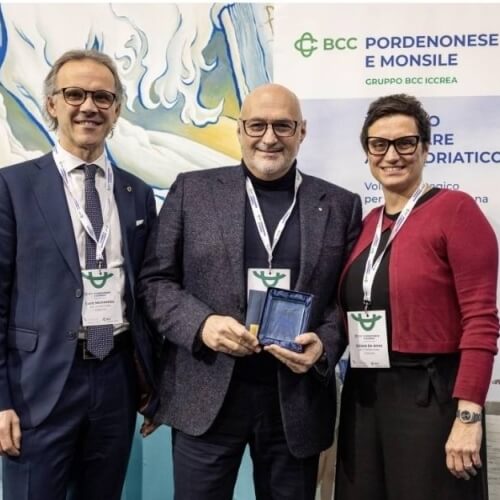 Tre persone con distintivi davanti a un banner BCC Pordenonese.